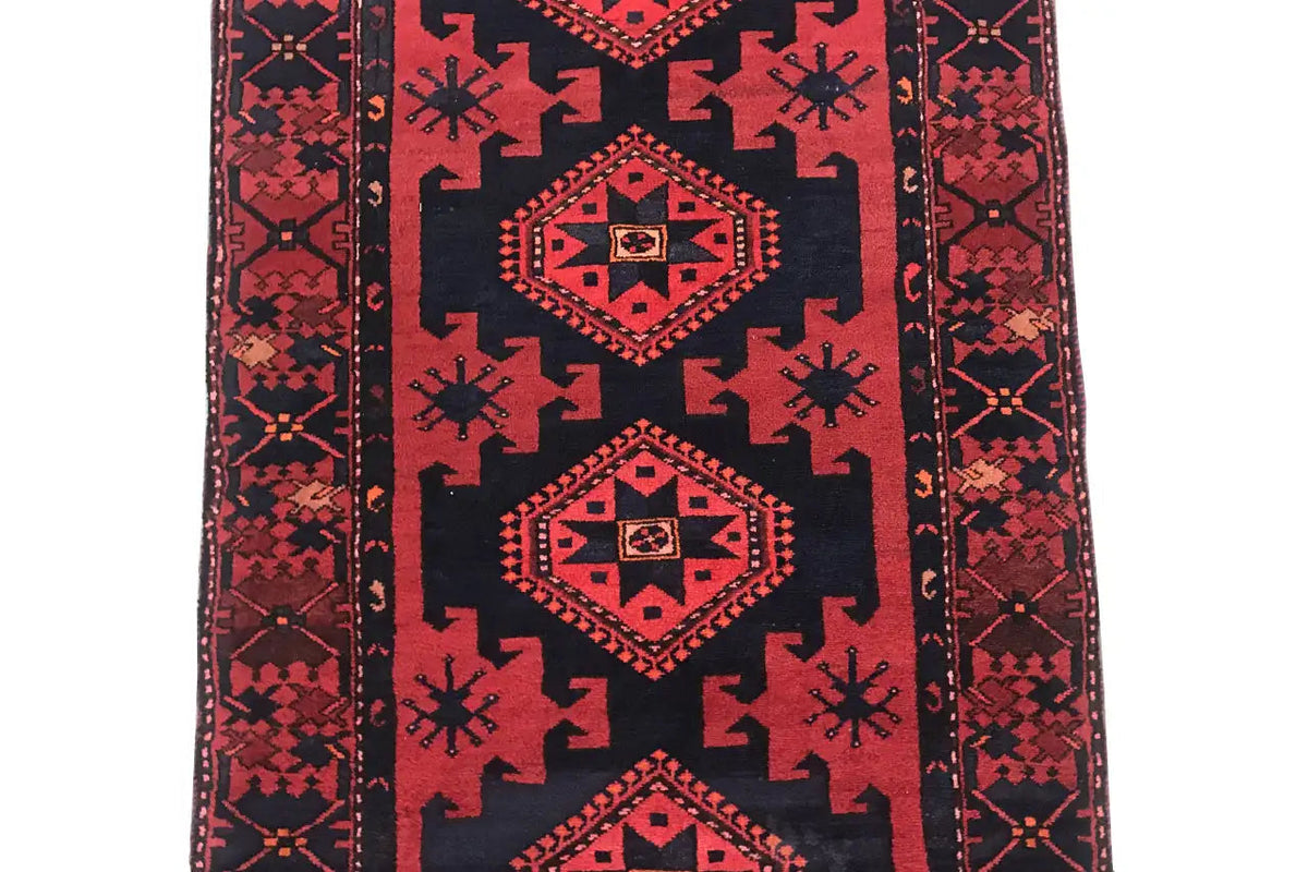 Runner rug with a dark blue field and red geometric medallions, clear decorative borders.