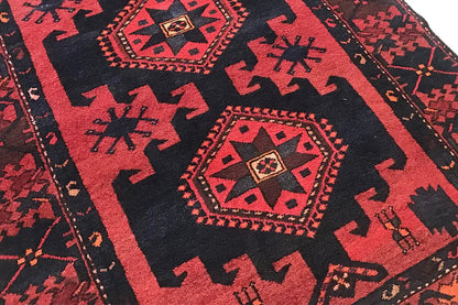 Close-up: red and blue decorative pattern with a medallion in the center, carpet pile visible.