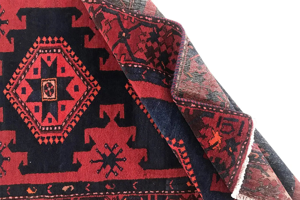 Geometrically patterned runner rug in red and dark blue, with a visible woven texture along the edge.