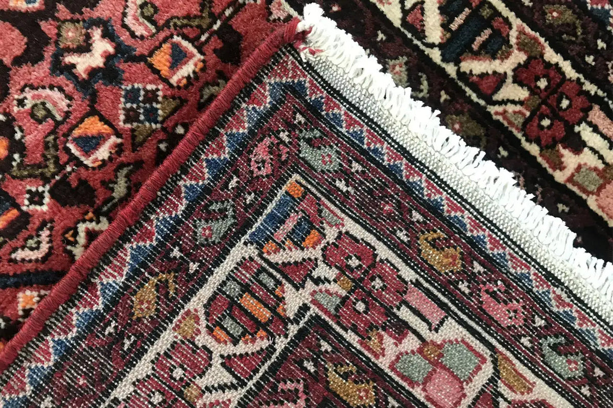 Close-up of a Hamadan runner: dense weave, turquoise-blue border, and fringes