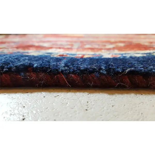 Rug cross-section: dark pile at the edge, with a multilayer carpet structure underneath