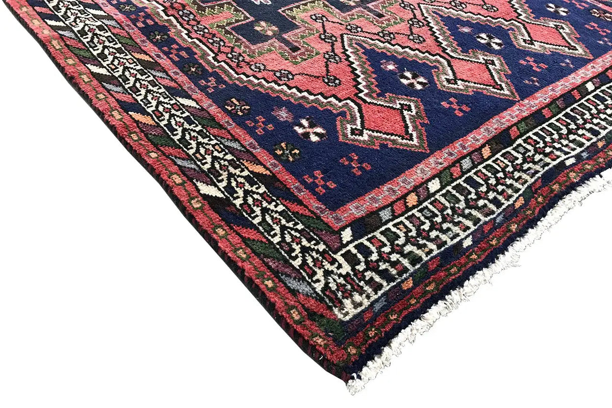 Sirjan runner rug corner: dark blue carpet with red accents, decorative border, and fringe