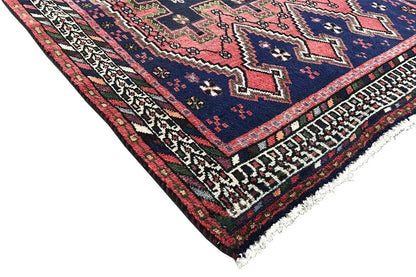 Sirjan runner rug corner: dark blue carpet with red accents, decorative border, and fringe