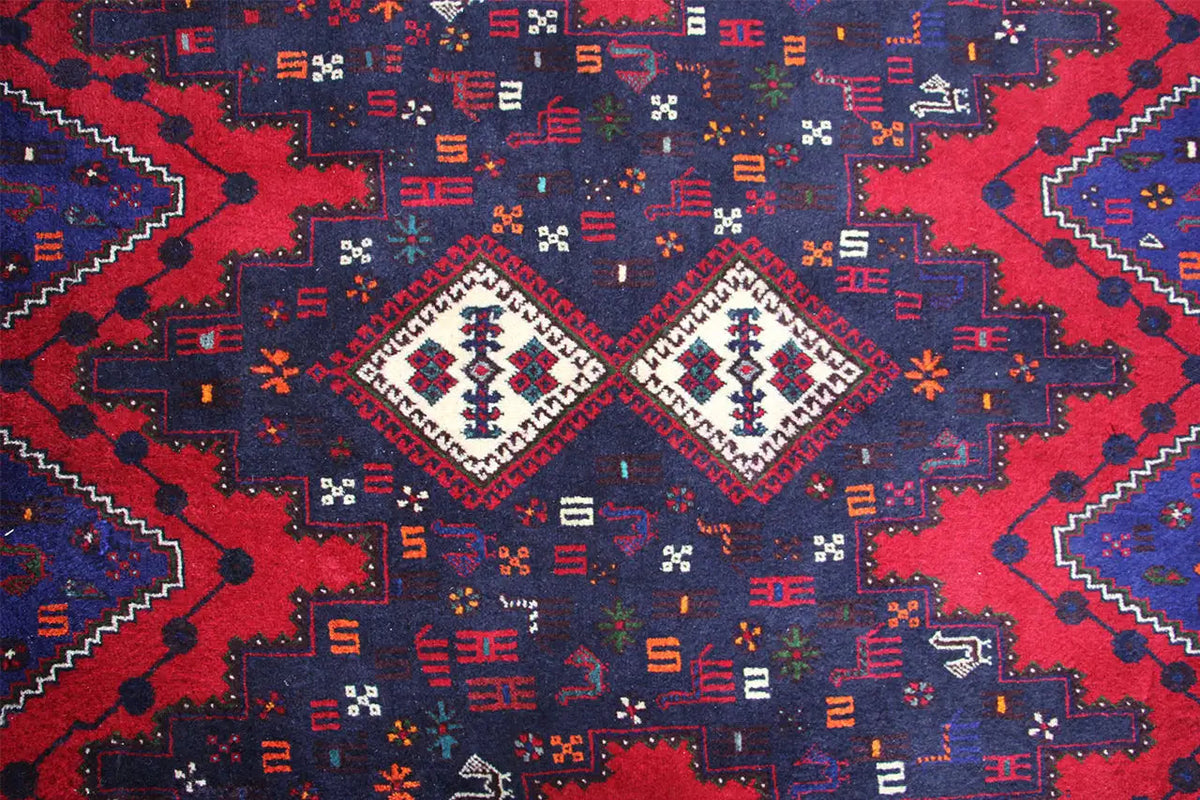 Close-up of a carpet pattern with diamonds and lines in red, blue, and white