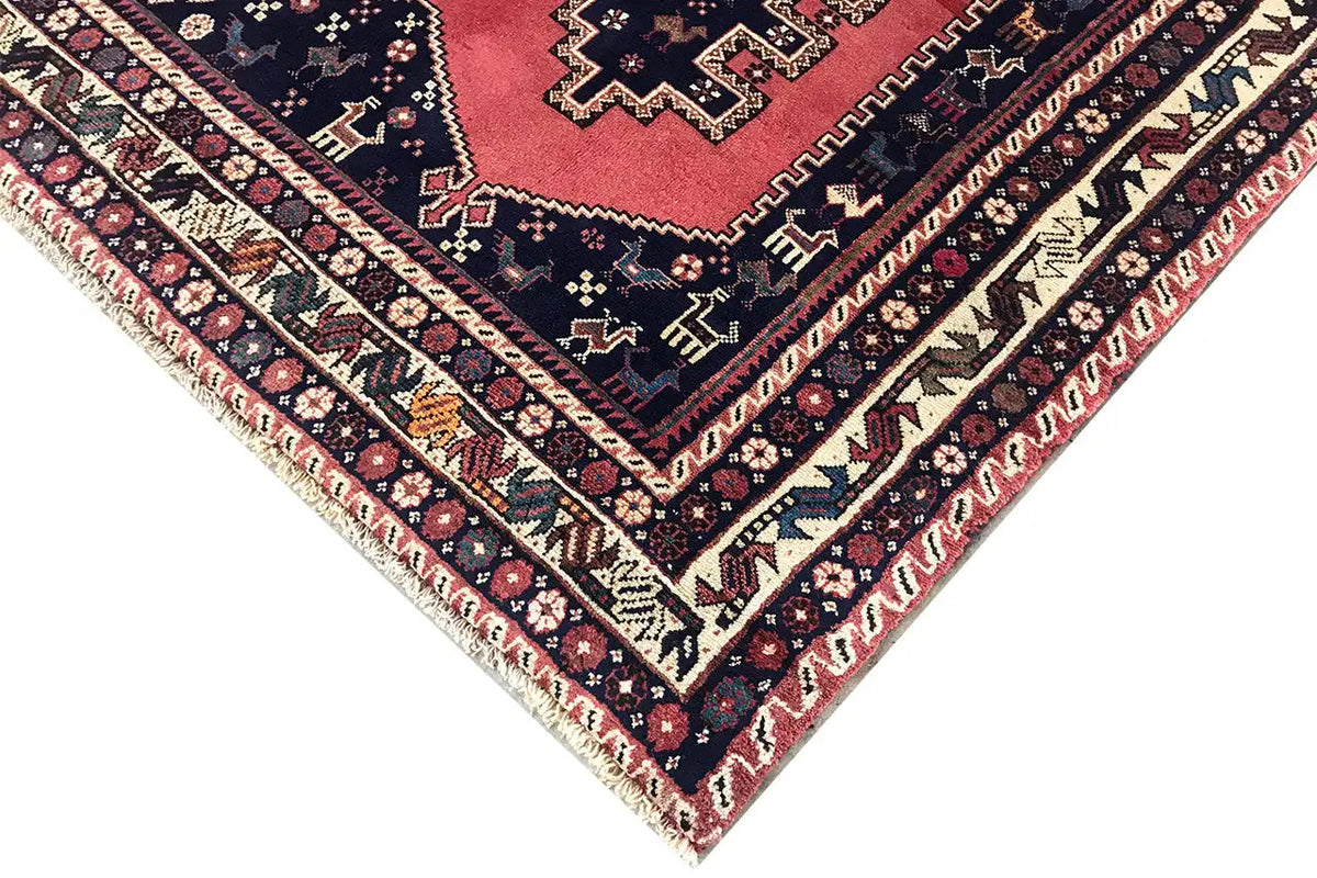 Oriental rug corner with fringe: dark blue, red, and cream-colored decorative lines