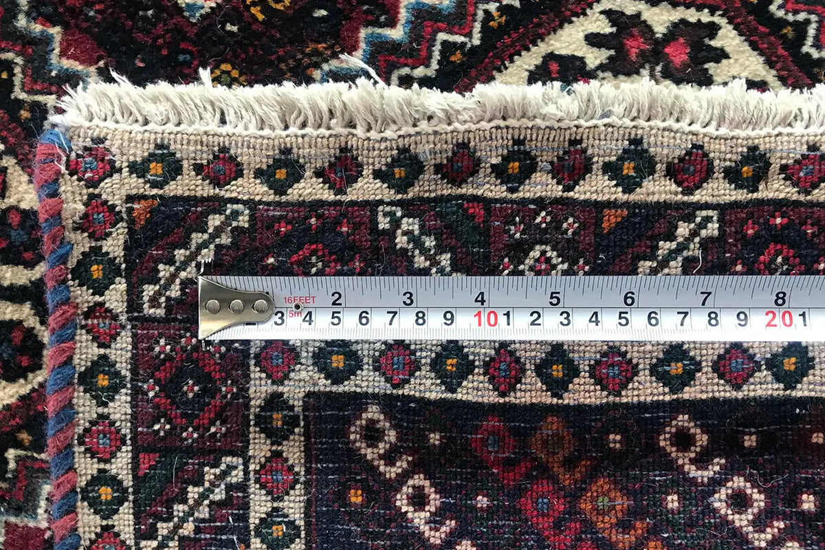 Close-up: measuring tape on runner, dotted ornamental border, and fringe