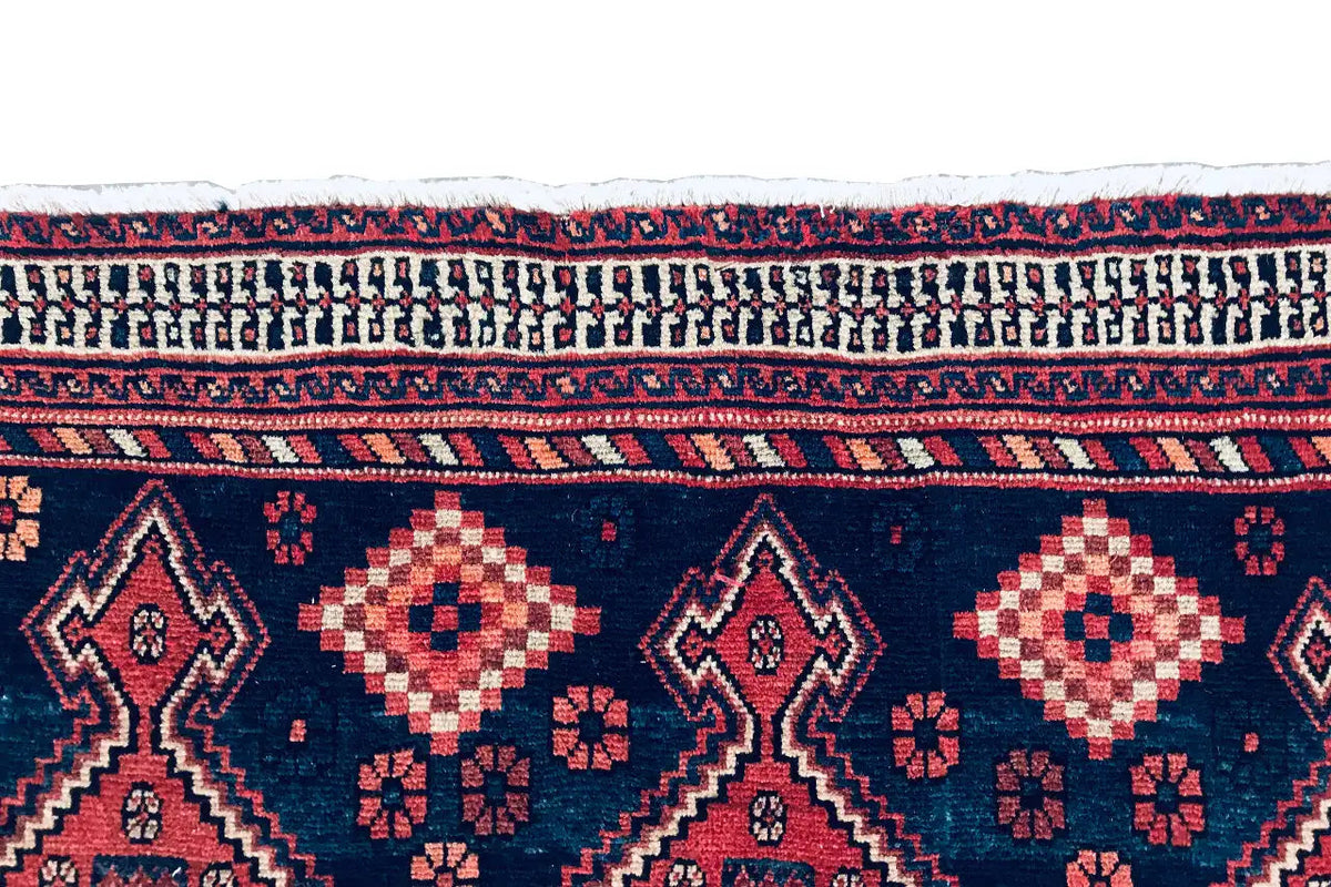 Carpet border in detail: dark blue with red-and-white patterns and decorative stripes