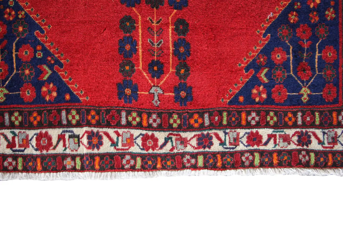 Red-and-blue rug with a geometric pattern and decorative border, with fringe