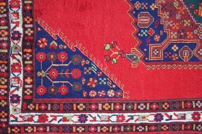 Close-up of a rug: red background with a blue decorative band, colorful flowers, and border
