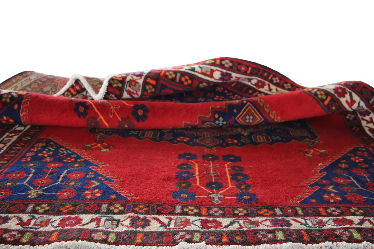 Folded carpet with a red background, blue decoration, and a border along the edges