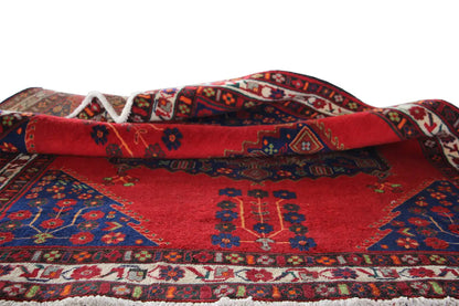 Folded carpet with a red background, blue decoration, and a border along the edges