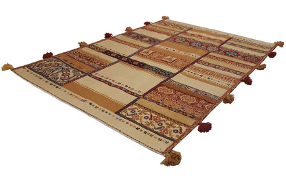Rug with a patchwork pattern in beige, red, and blue, with tassels at the corners.