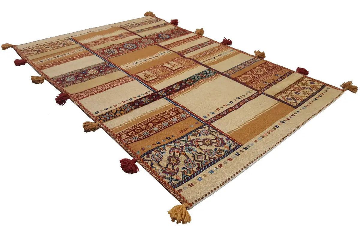 Rug with a patchwork design in beige, brown, red, and blue, with tassels at all four corners.