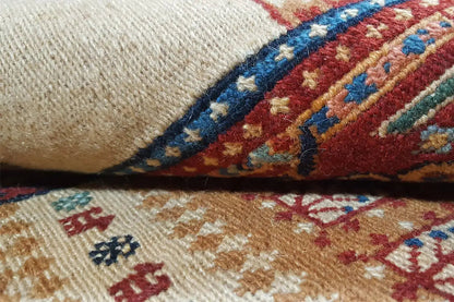 Carpet fabric with a woven pattern in beige, red, and blue, with visible texture in detail.