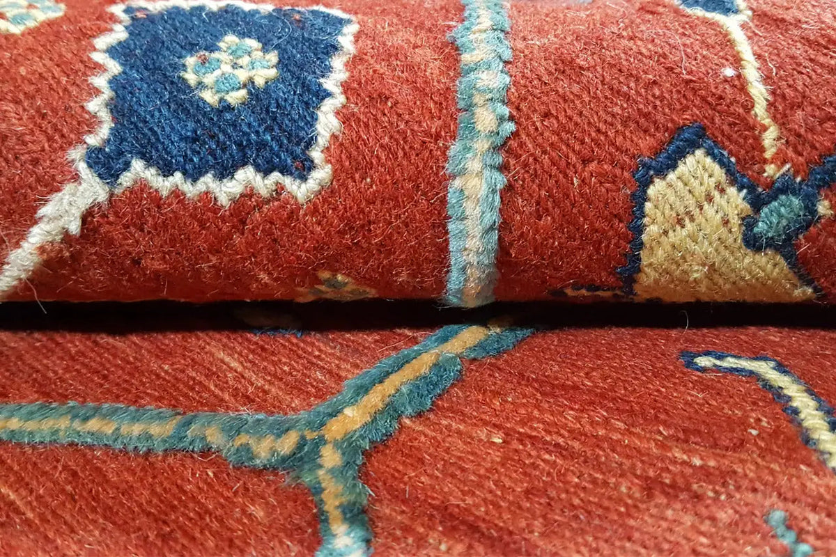 Close-up of a red carpet with blue-green borders and visible pile texture