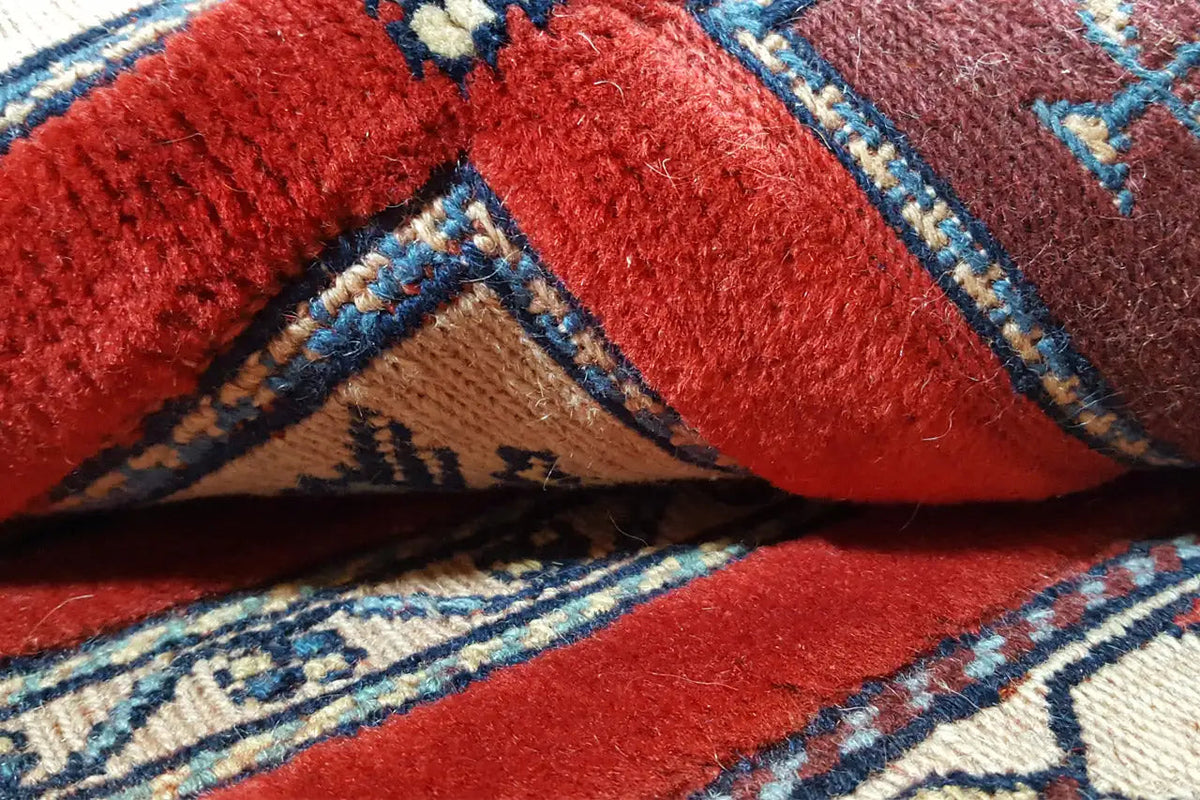 Rug detail: red pile with blue stripes and beige borders, decorative patterns