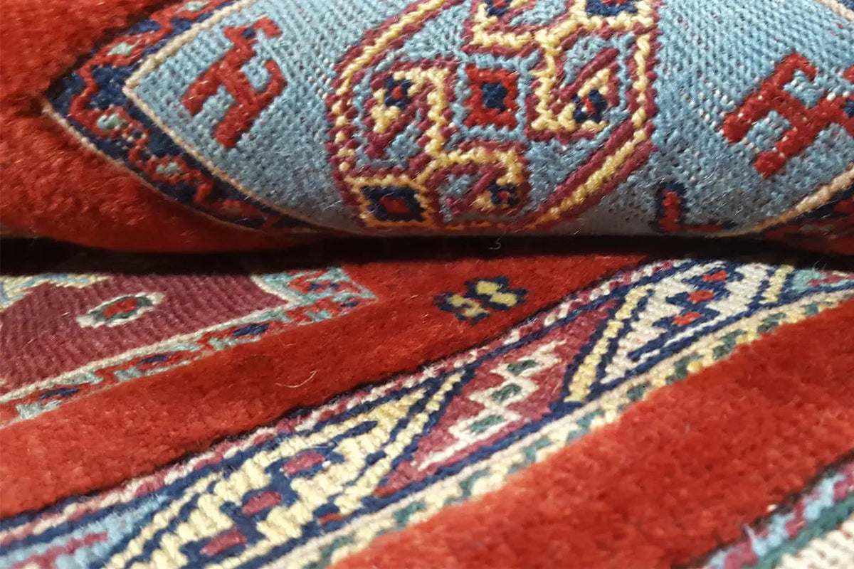 Detail of an Oriental rug: red field, blue and yellow ornaments, woven texture