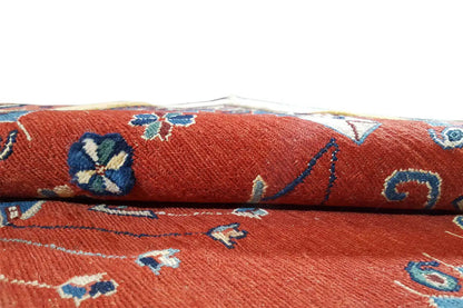 Close-up: red rug with blue-beige floral patterns and fringes