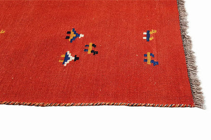 Red kilim rug with multicolored pattern elements and fringed border