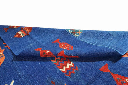 Blue kilim rug with red and turquoise patterns, close-up