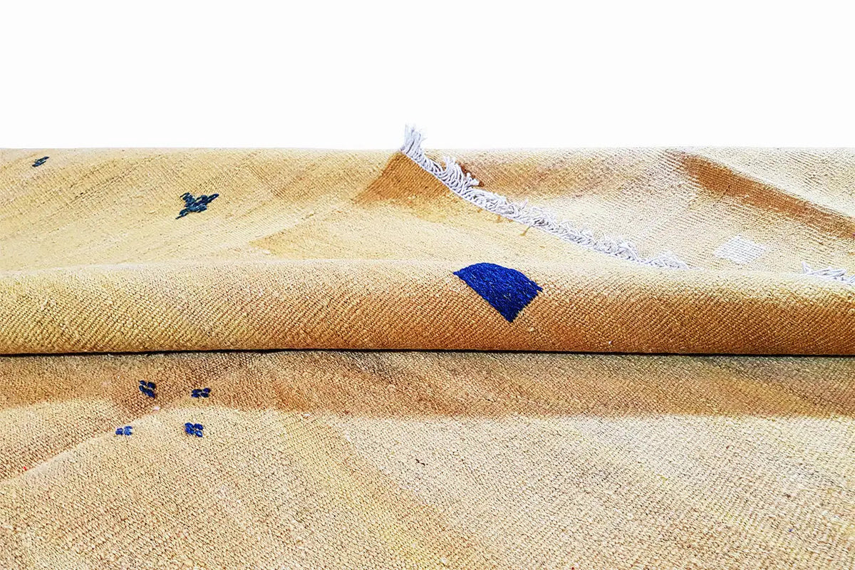 Ochre kilim rug with blue detail and fringes, woven fabric texture