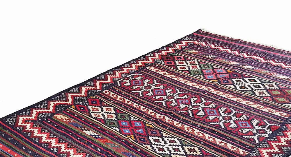 Detailed view of kilim rug: colorful ornaments, stripes, and zigzag edges, dark blue
