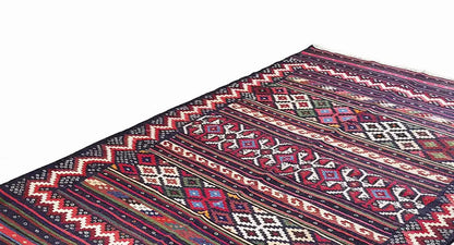 Detailed view of kilim rug: colorful ornaments, stripes, and zigzag edges, dark blue