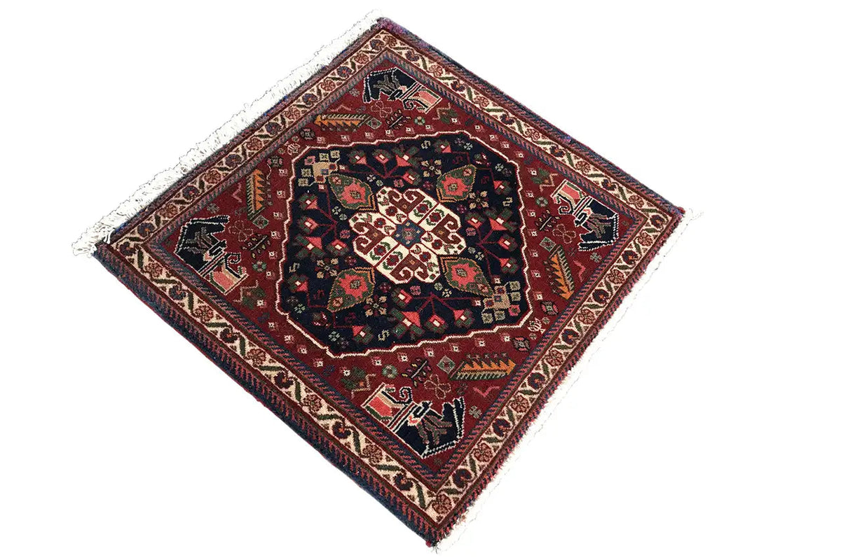 Square rug with a geometric central pattern in dark blue, red, and beige tones