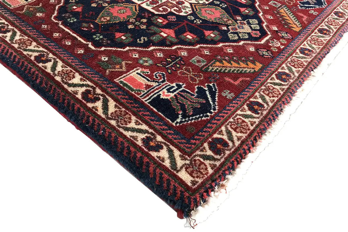 Corner view of a rug with a colorful bordered edge and white fringes