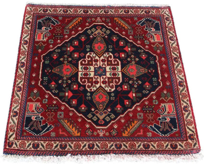 Qashqai rug by Poschti: red oriental rug with a dark blue medallion and fringes.