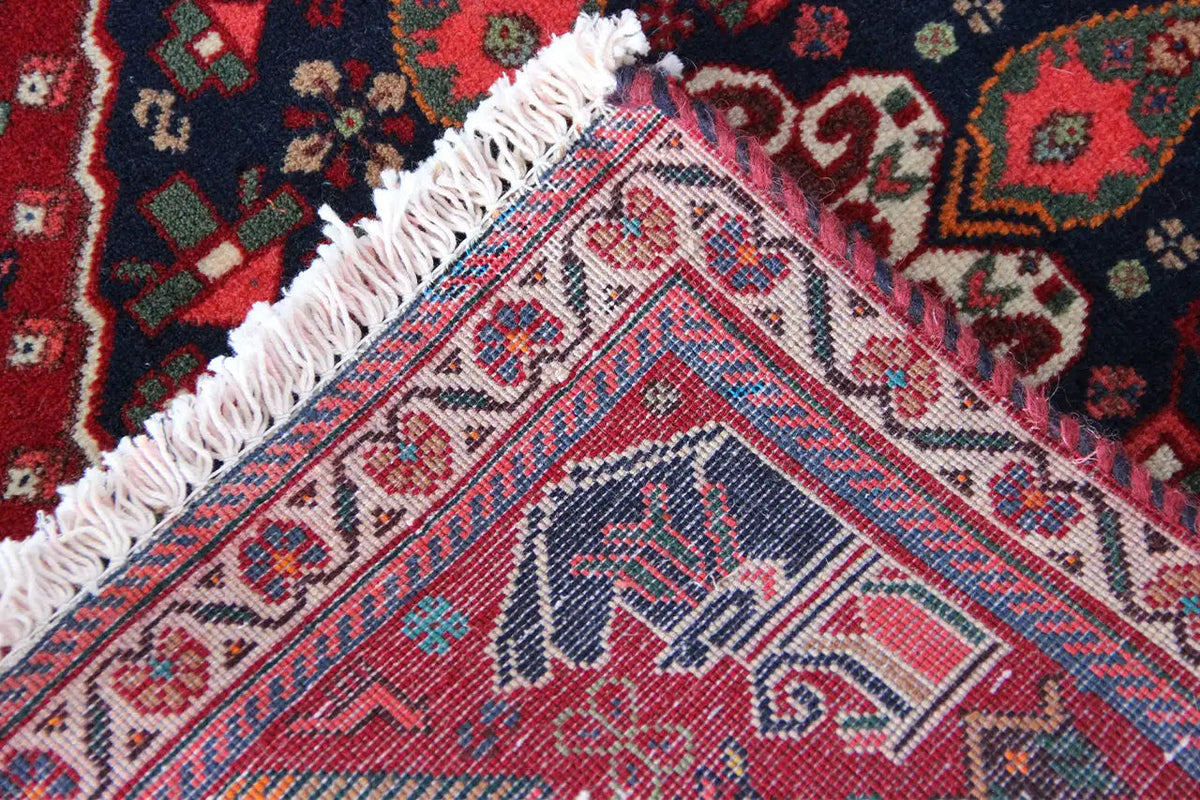 Qashqai rug by Poschti: detail near the corner, woven pattern with fringed trim.