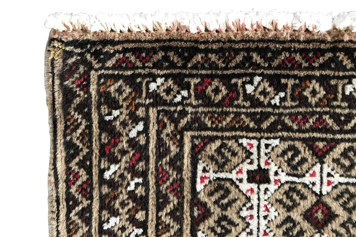 Close-up of a Turkmen carpet: bordered trim with a dark background and small red accents