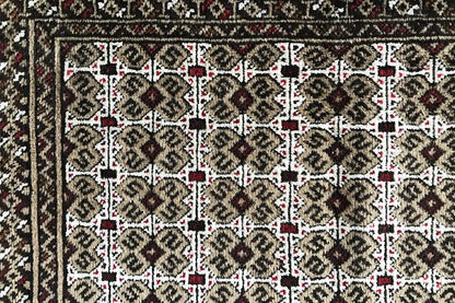 Turkmen carpet detail view: rectangular field with rows of ornaments in beige and dark brown