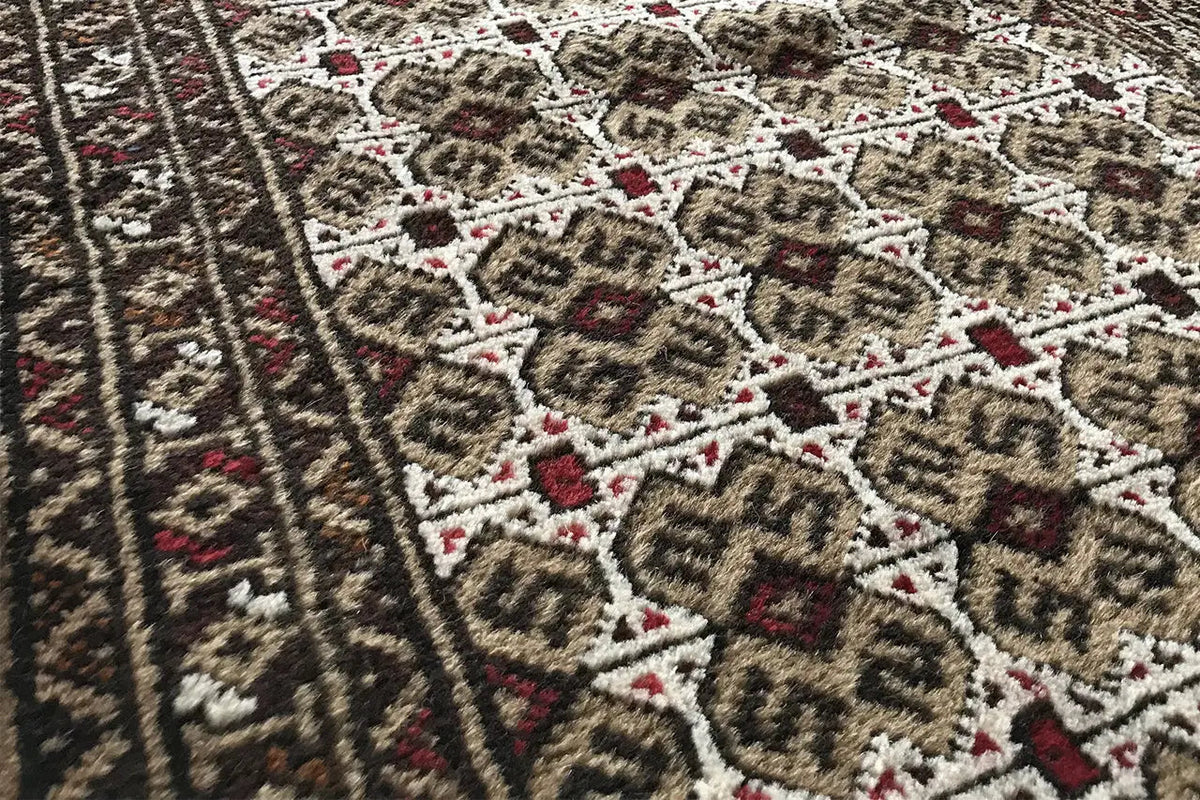 Turkmen carpet detail: dense pile with geometric motifs in brown, beige, and red