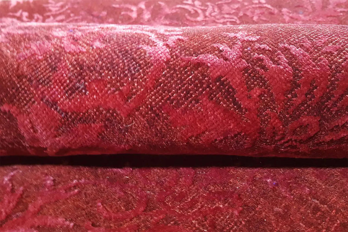 Deep burgundy carpet with baroque damask ornamentation and a fine weave texture