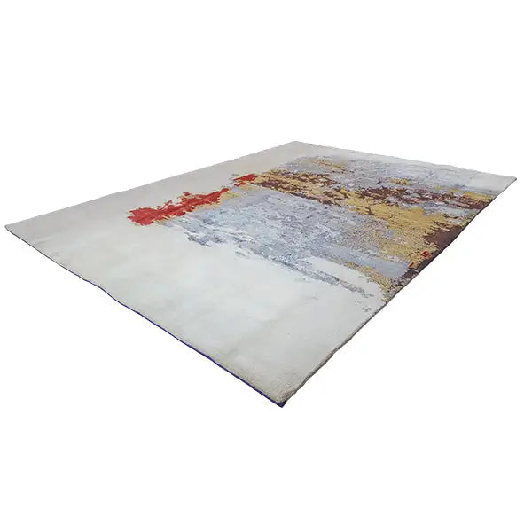 Designer rug at an angle, light gray with blue and yellow color splashes