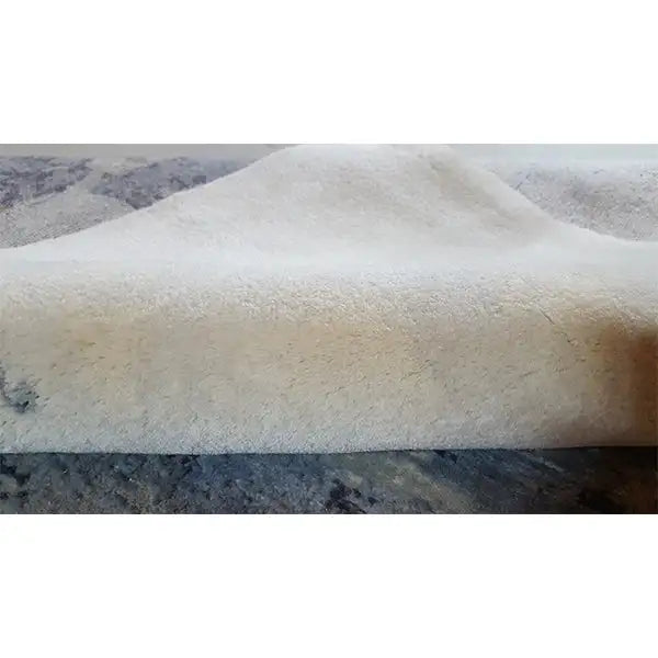 Designer rug close-up: light pile surface with a blue-gray abstract blotch