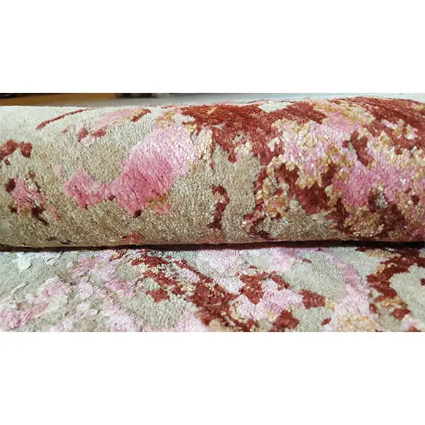 Carpet detail with pile and an abstract pattern in red, pink, and beige