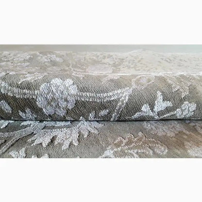 Carpet with a gray pile and floral ornaments in the close-up area, including edge stitching