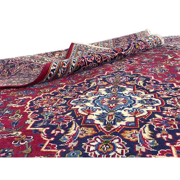 Roll of carpet with red pile and blue-and-white ornaments; visibly rolled edge