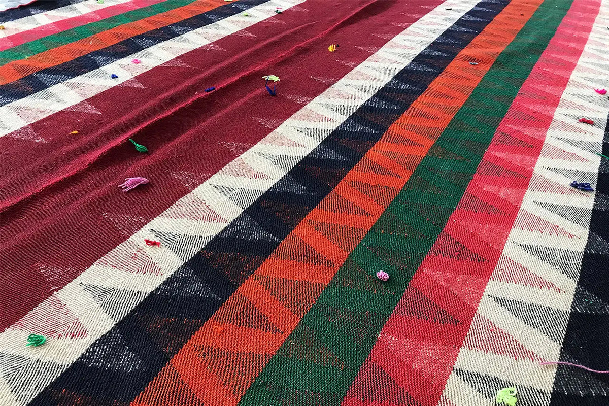 Close-up of a Jajim rug: striped pattern with small colorful yarn tassels