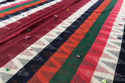 Close-up of a Jajim rug: striped pattern with small colorful yarn tassels