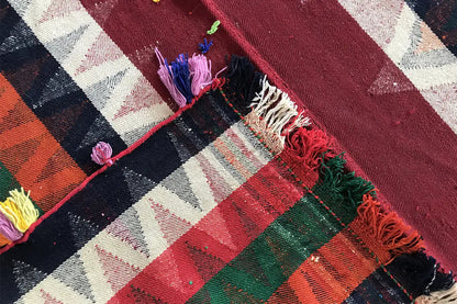 Jajim rug detail: red and dark blue stripes with frayed edges and yarn tassels