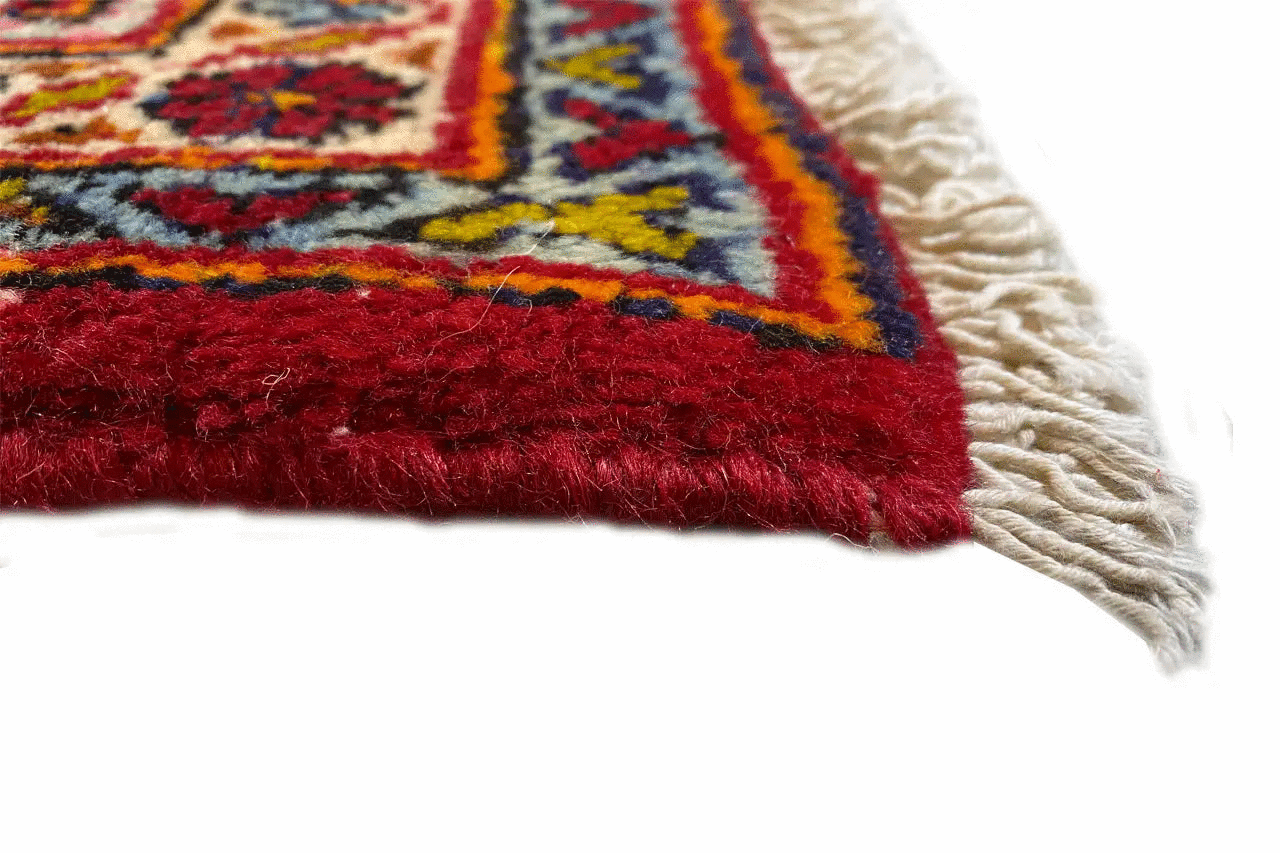 Fringe on the edge of the red Oriental rug, detail of the woven decorative border