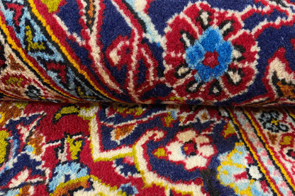Detail of a red oriental rug with blue-yellow ornaments and a small pattern