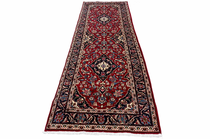 Red oriental rug with a vine and medallion pattern and blue border