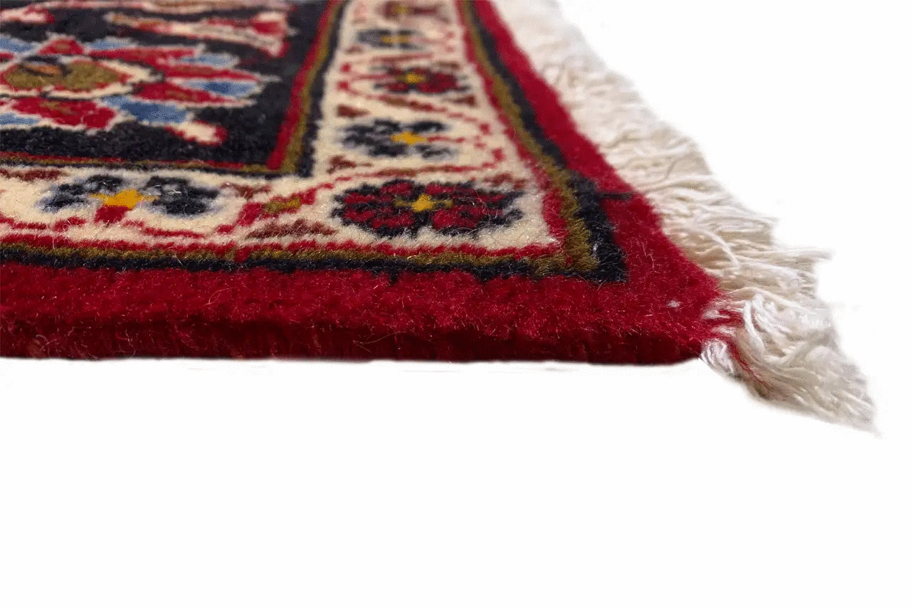Keshan runner rug: detail at the edge with fringe, a red pattern, and dark blue edging