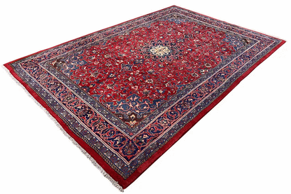 Rectangular red rug with a blue medallion and ornamental pattern