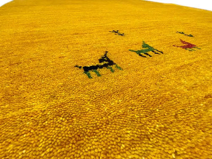 Close-up: yellow Gabbeh rug with a dense pile and colorful animal motifs