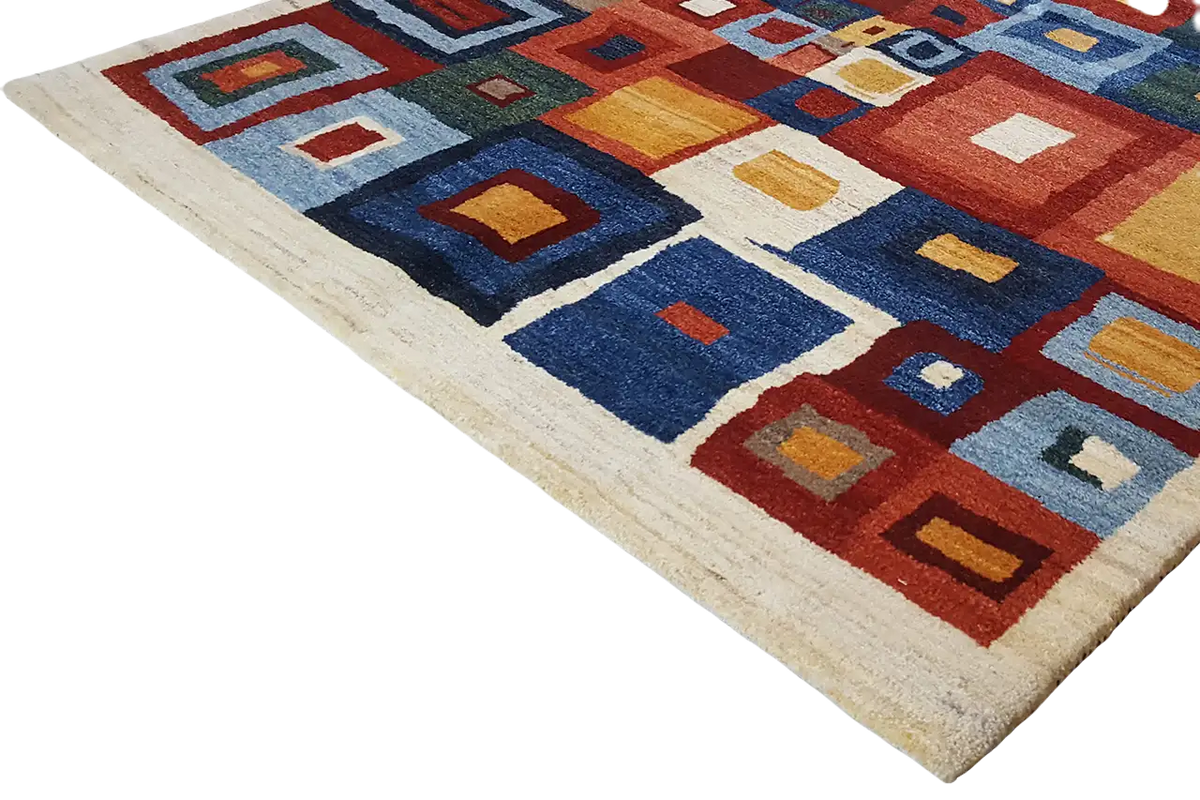 Corner view of a Gabbeh rug with geometric squares in blue, red, and beige